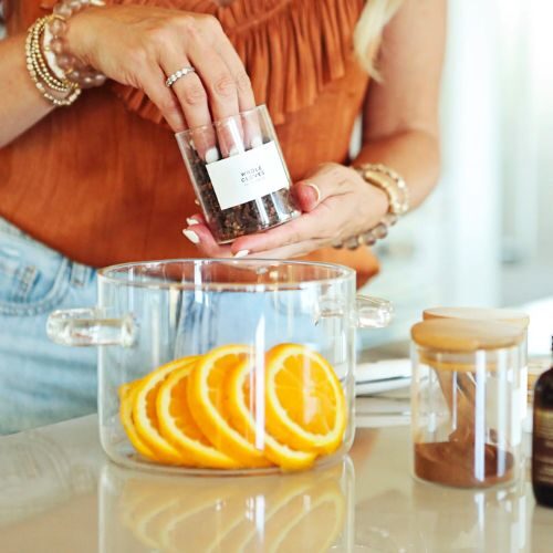 Woman adding cloves to orange slices.