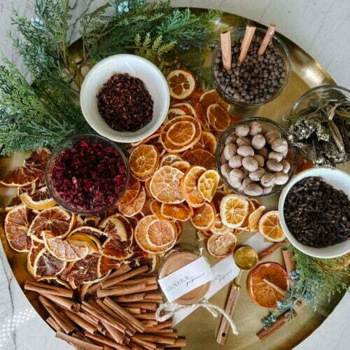 Spices, dried oranges, and cinnamon sticks on a tray.