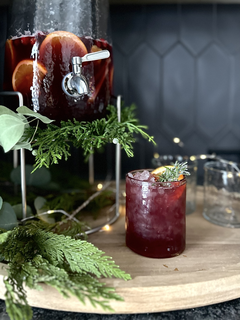 Red sangria with orange and rosemary garnish.