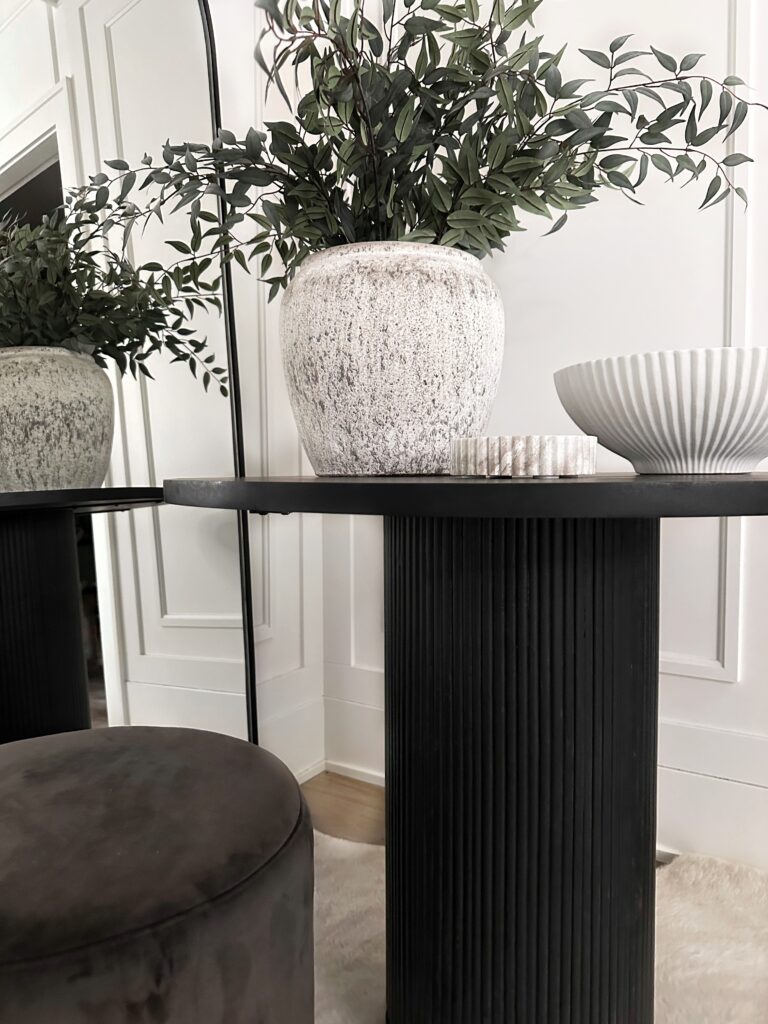 Black table with a white vase and bowl.