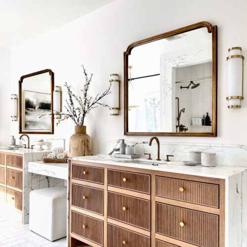 Modern bathroom with wooden vanity and gold accents.