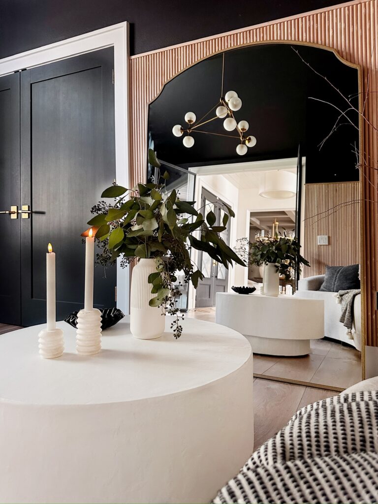 White candles and vase on a coffee table.