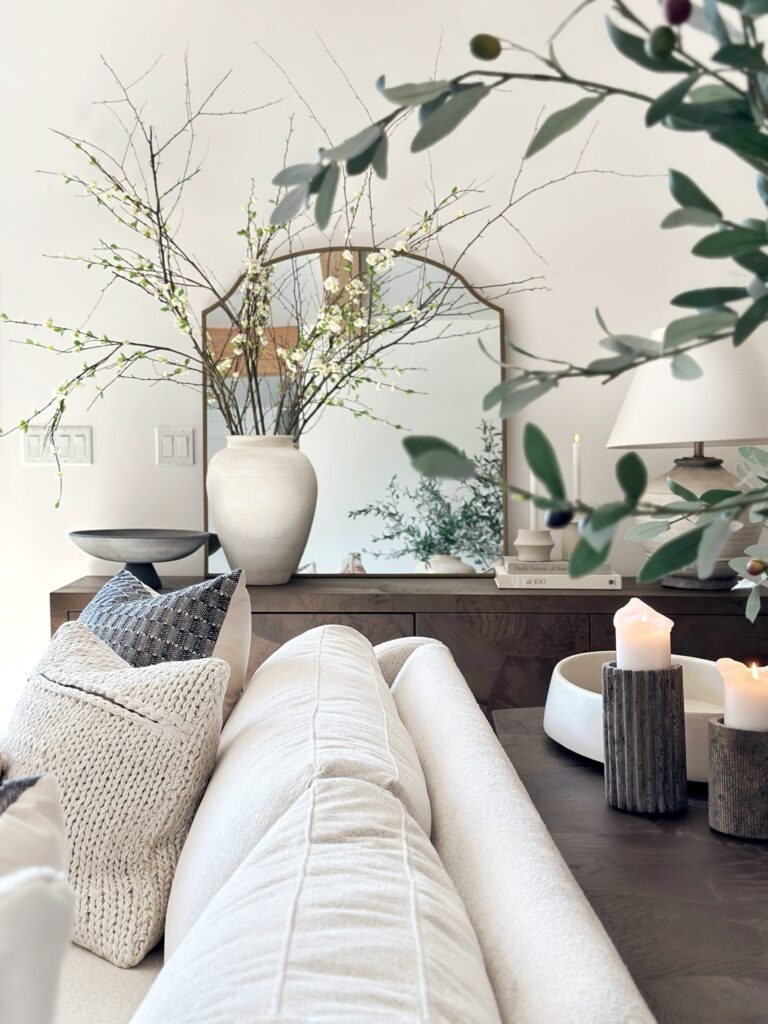 White couch with floral arrangement and candles.