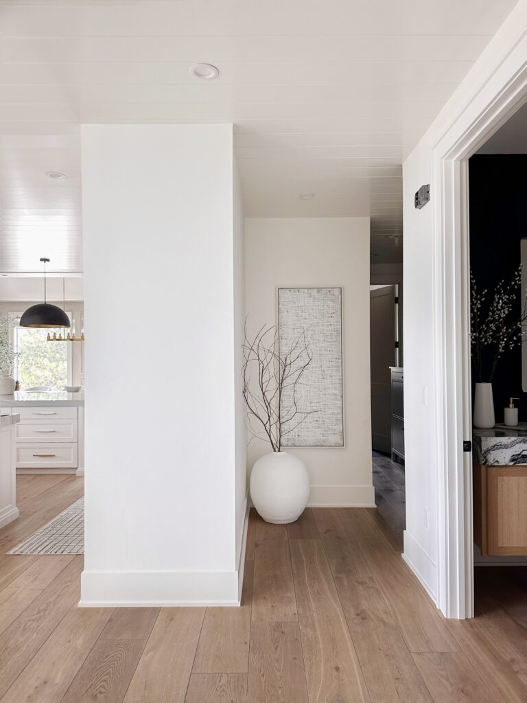 White hallway with wood floor and artwork.