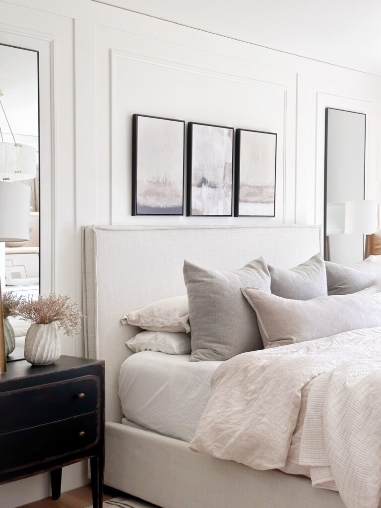 White bed with neutral bedding and artwork.