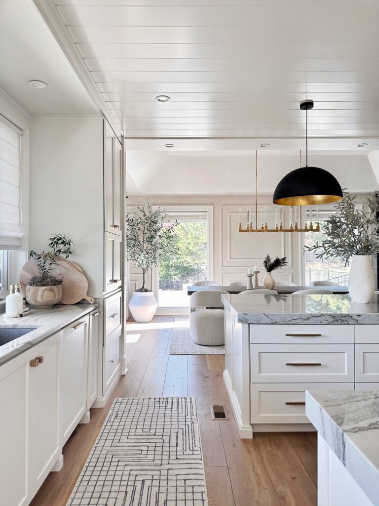 White kitchen with marble island and rug.