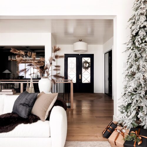 White couch and snowy Christmas tree in living room.