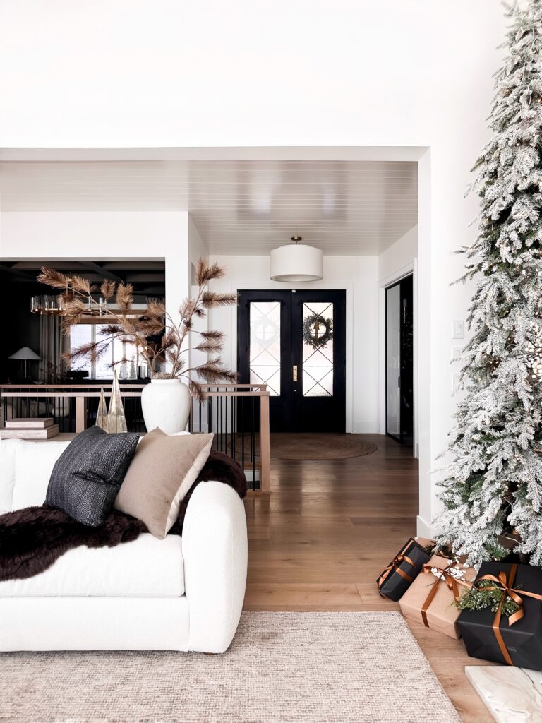 White couch with pillows near a Christmas tree.