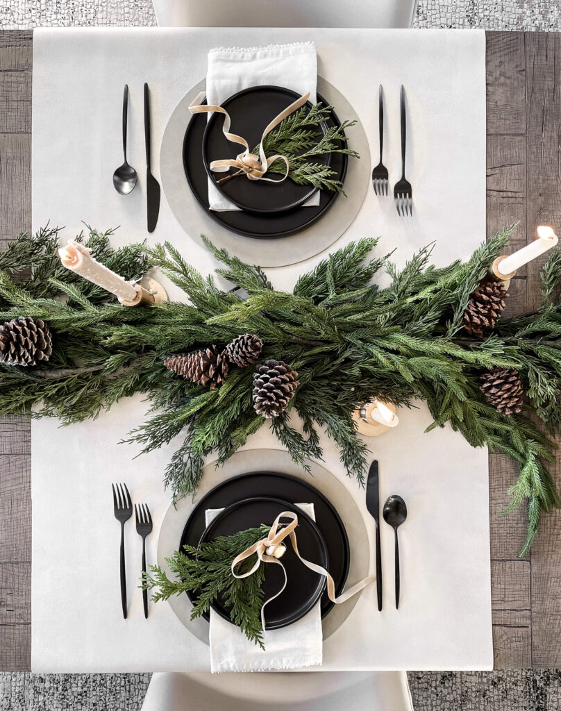 Christmas table setting with greenery and pine cones.