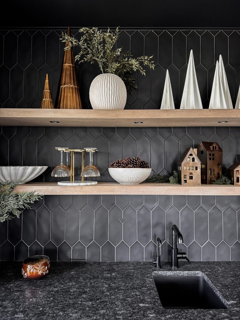 Black kitchen with wood shelves and sink.