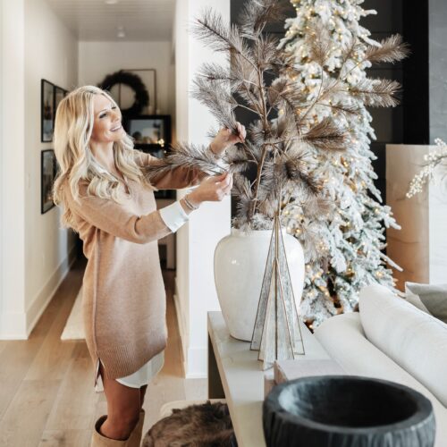 Woman decorating with a snowy Christmas tree.