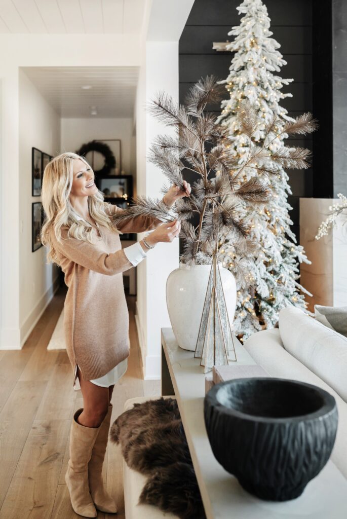 Woman decorating with a snowy Christmas tree.