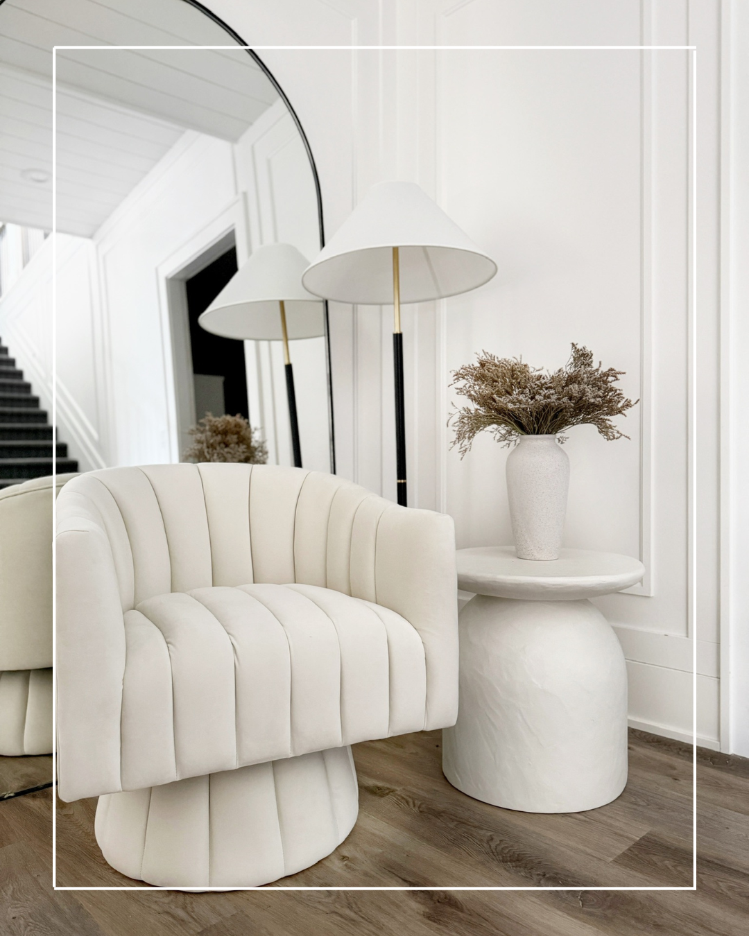 White tufted chair with side table and lamp.