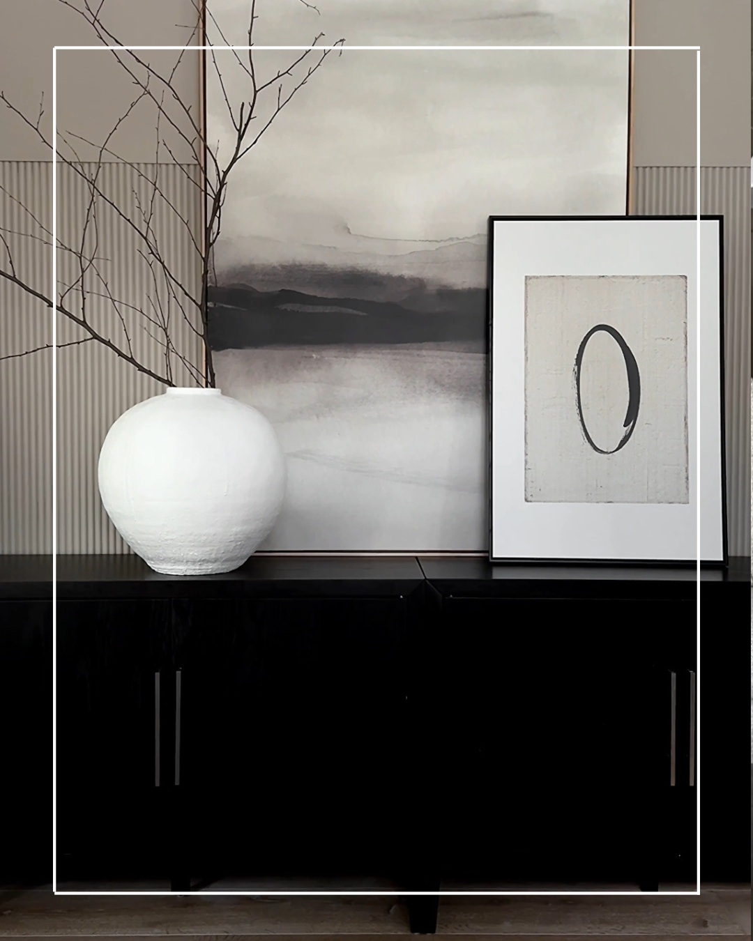 White vase, framed art on black console.