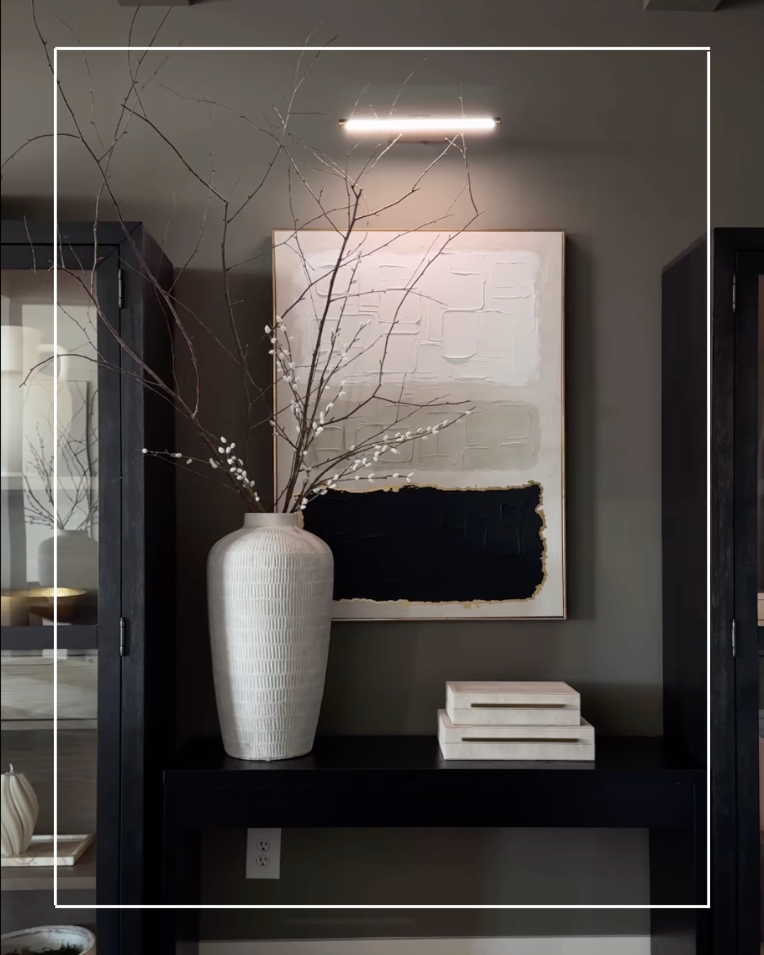 White vase and abstract art on a console table.