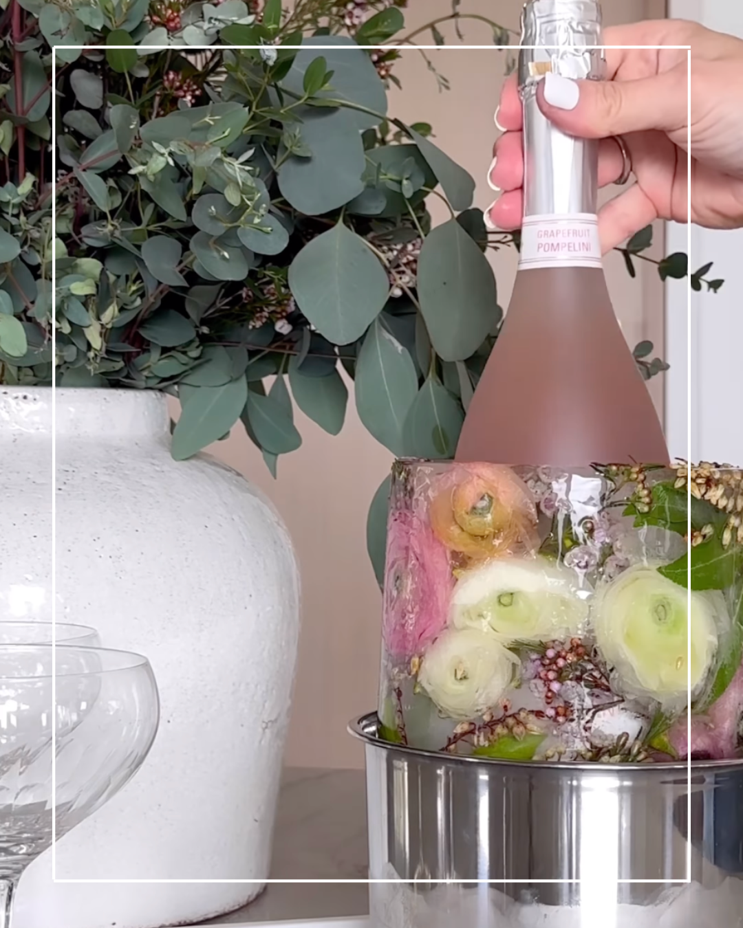 Pink champagne bottle in floral ice bucket.