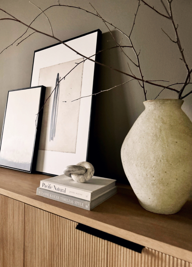 White vase with dried branches and art.