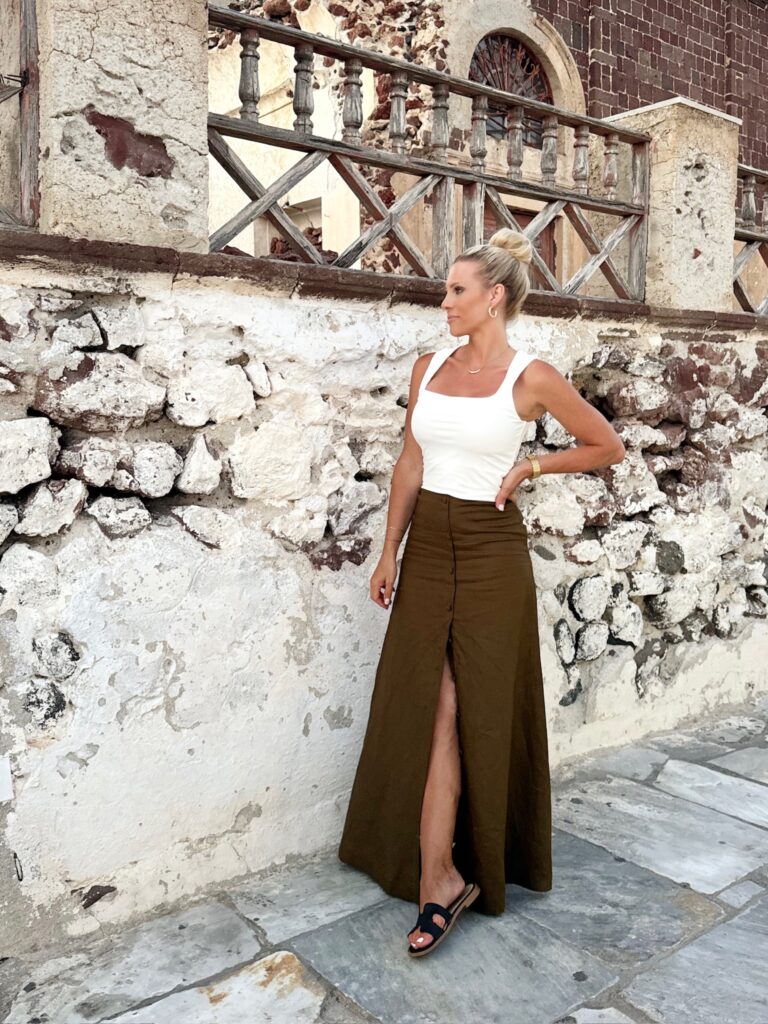 Woman in a white tank top and brown skirt.