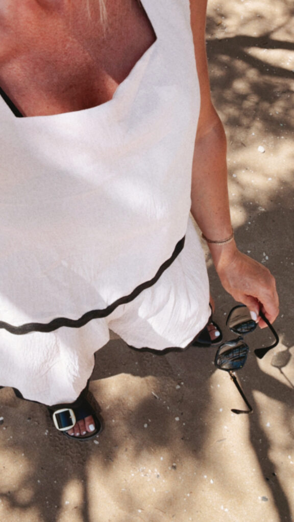 Woman in white dress on sandy beach.